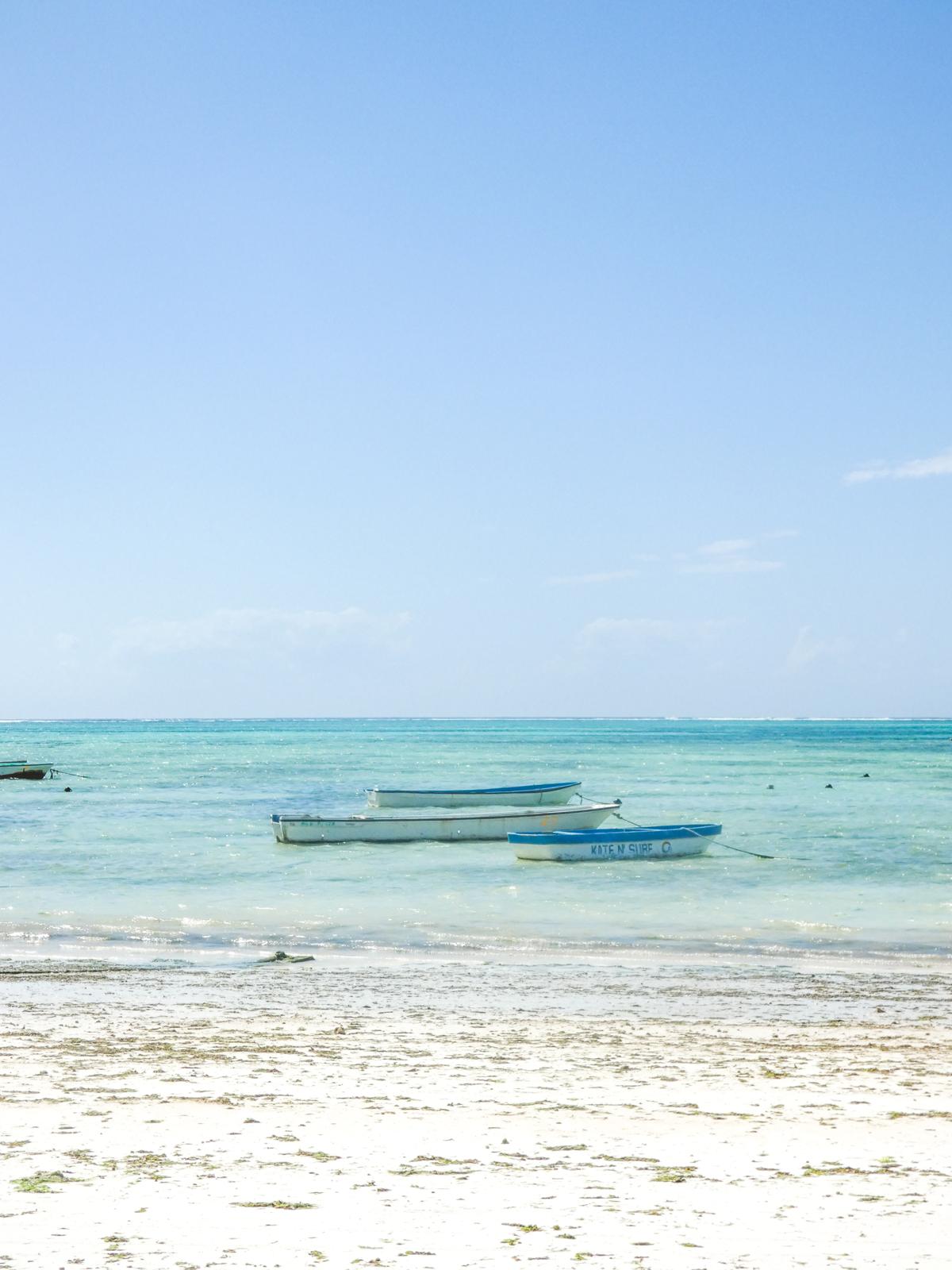 Wooden boats resting on the turquoise shallows of Paje beach, Zanzibar
